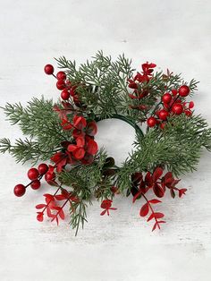 a christmas wreath with red berries and greenery on a white background, ready to be used as an ornament