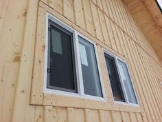 the side of a wooden building with three windows on each side and one window in the middle