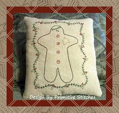 a decorative pillow with a hand embroidered gingerbread man on it, sitting on a quilted surface