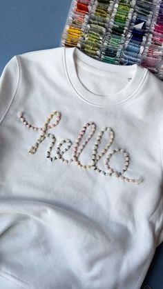 a white shirt with the word hello written on it next to colored crayons