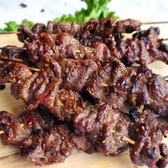 several skewers of meat sitting on top of a wooden cutting board