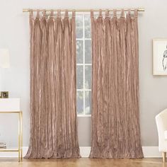 a living room with a white chair and beige curtains on the window sill in front of it