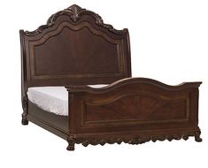 an ornate wooden bed frame with white sheets