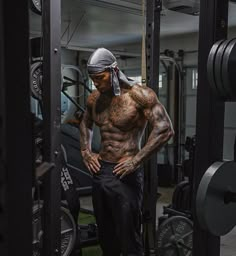 a man standing in front of a gym machine with his hands on his hips while wearing a bandana