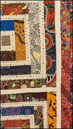 a close up of a quilt with many different colors and patterns on the fabric,