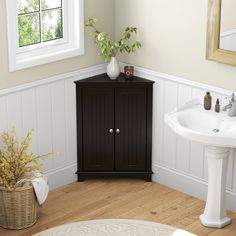 a white sink sitting next to a wooden cabinet in a bathroom on top of a hard wood floor