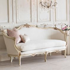 a white couch sitting in front of a chandelier