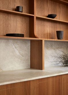 a kitchen with wooden cabinets and white marble counter tops, black bowls on the shelves