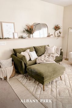 a living room with a green couch and ottoman in the corner, white walls and rug on the floor