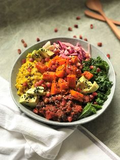 a bowl filled with different types of food on top of a white cloth next to utensils