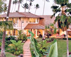 a house with palm trees in the front yard and walkway leading up to it's entrance