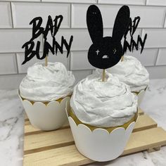 two cupcakes with white frosting and black bunny ears