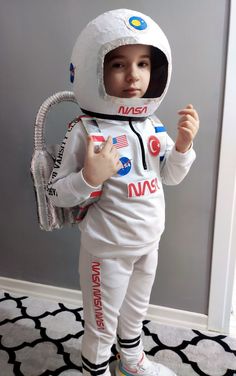 a young boy wearing an astronaut suit and holding a tennis racquet in his hand