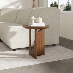 a white couch sitting next to a wooden table on top of a rug in a living room