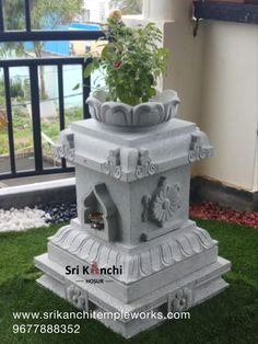 a stone fountain with plants in it on the grass near a building and window sill