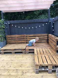 a small child is sitting on a wooden bench made out of pallets and crates