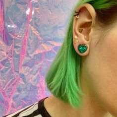 a woman with green hair wearing ear piercings