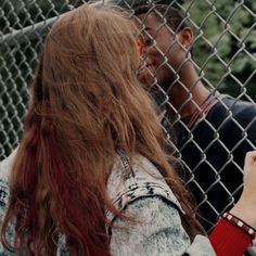 a person leaning against a fence holding a cell phone