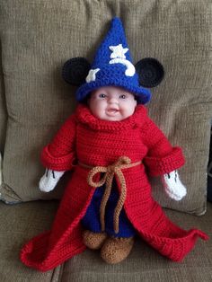 a crocheted doll dressed in a red and blue outfit sitting on a couch