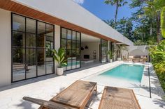 an outdoor swimming pool with lounge chairs and palm trees in the foreground, surrounded by greenery