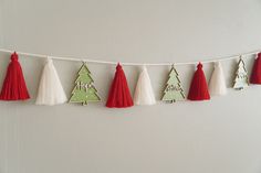 christmas decorations are hanging on a string with tassels and ornaments in the shape of trees