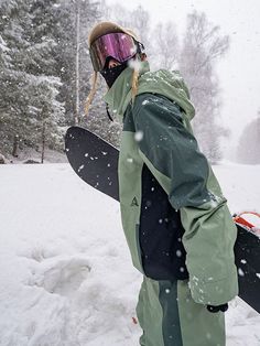 a snowboarder is carrying his board through the snow