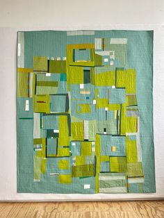 a green and white quilt hanging on the wall