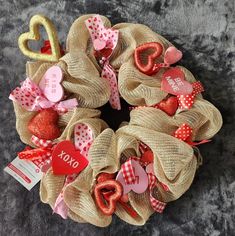 a burlock wreath decorated with hearts and ribbons on top of a gray carpet