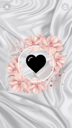 a black heart surrounded by pink flowers on a white satin background with the word love