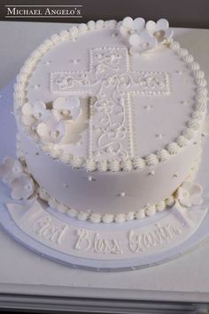 a white cake decorated with flowers and a cross on it's side is shown