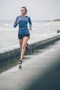 a woman is running along the water