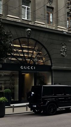 a black truck parked in front of a building with a sign that says gucci