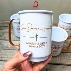 a woman holding three coffee cups with the name medical urn turma on them