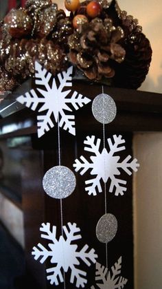 snowflakes and pine cones are hanging from a mantle