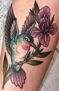 a hummingbird with purple flowers on it's thigh