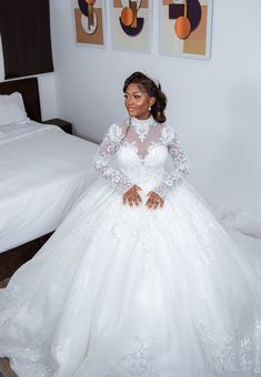 a woman in a white wedding dress sitting on a bed with her hands on her hips