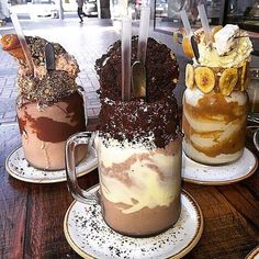 three desserts are sitting on plates with spoons in each mug and one is filled with ice cream