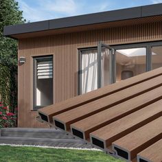 a wooden deck with sliding glass doors in front of a house that is brown and has white curtains on it