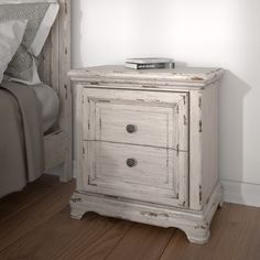 an old white nightstand with two drawers in a bedroom next to a bed and night stand