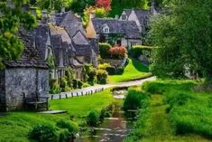 a river running through a lush green countryside next to small houses on the side of a road