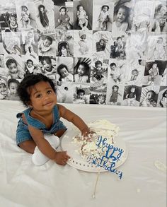 a baby sitting on a bed with a birthday cake