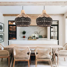 the dining room table is surrounded by wicker chairs and rattan pendant lights hanging from the ceiling