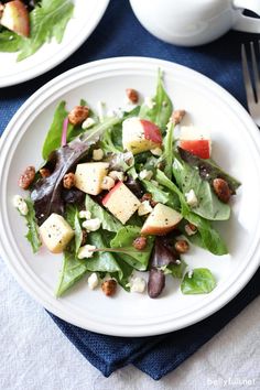 a white plate topped with salad on top of a blue cloth next to a fork