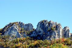 the mountains are covered with trees and rocks in fall colors, against a blue sky