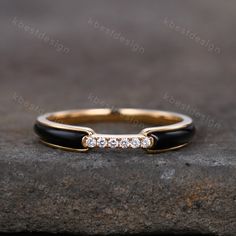 a gold ring with black onyxite and white diamonds is sitting on a rock