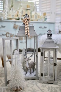 two small lanterns are sitting on the floor next to a christmas tree and other decorations