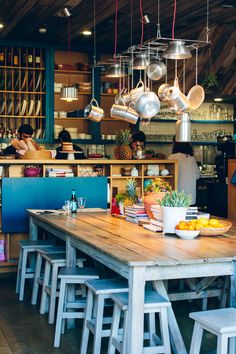 a wooden table sitting in front of a kitchen filled with lots of pots and pans