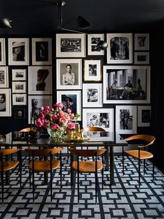 a dining room table with chairs and pictures on the wall behind it in black and white