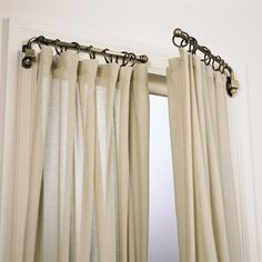 an open window with white curtains and black metal hardware on the curtain rod, in front of a mirror