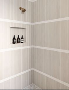 a bathroom with three bottles on the wall and two soap dispensers in the corner